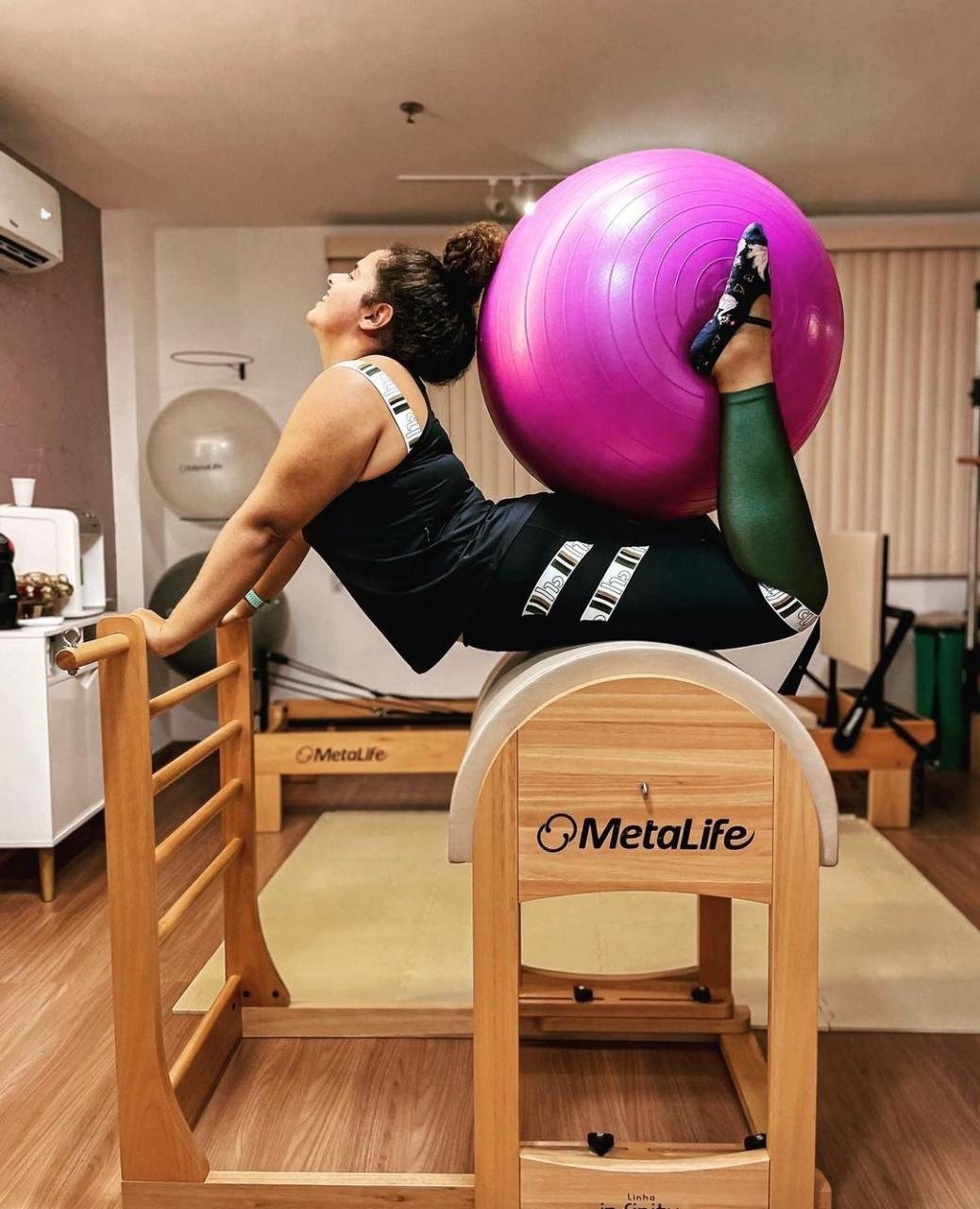 Aluna fazendo exercício de Pilates no barril com bola